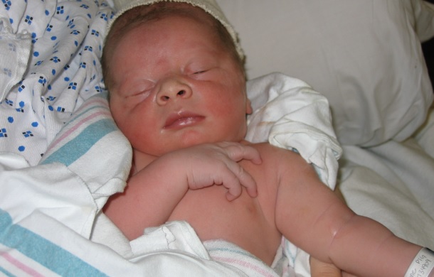 Image is a stock photo showing a newborn infant sleeping.