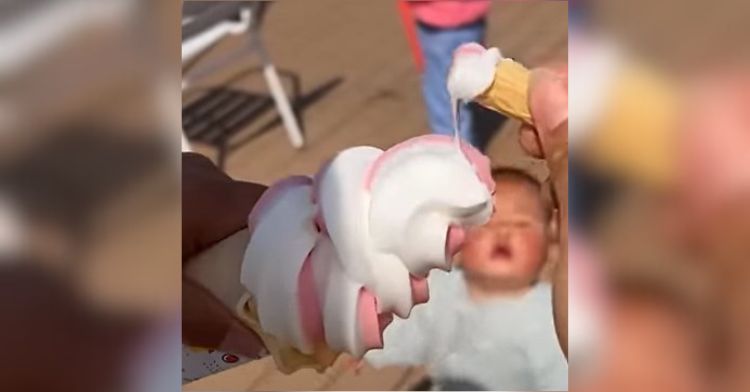 Image shows an ice cream cone with a small toddler in the background.