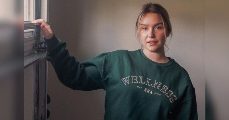 Image shows a model wearing a "Wellness ERA" sweatshirt from Unfinished Apparel. The company is trying to replace the use of paper scrubs in psychiatric facilities.