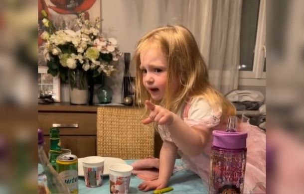A tiny tot passionately telling an adult to apologize to her grandma. The small child is pointing and speaking passionately.