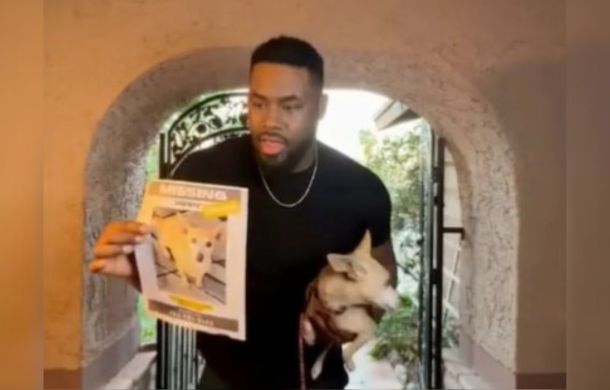 a stranger found a missing pup and was returning her to the owner. Image shows the man, holding the dog and a flyer about the dog up to a Ring doorbell camera.