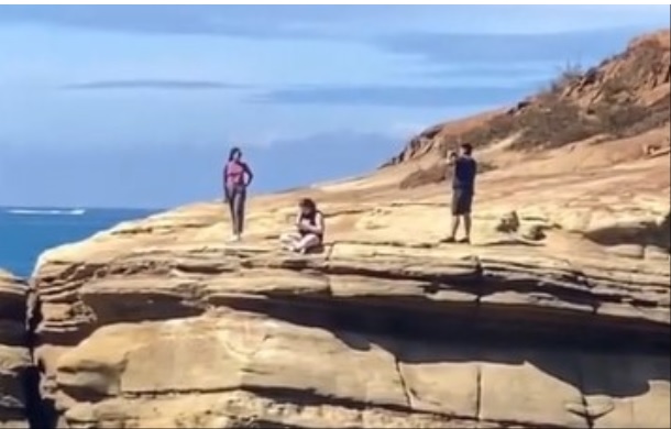 Image is a close up of the first image, showing exactly how close to the edge the people are standing and sitting.