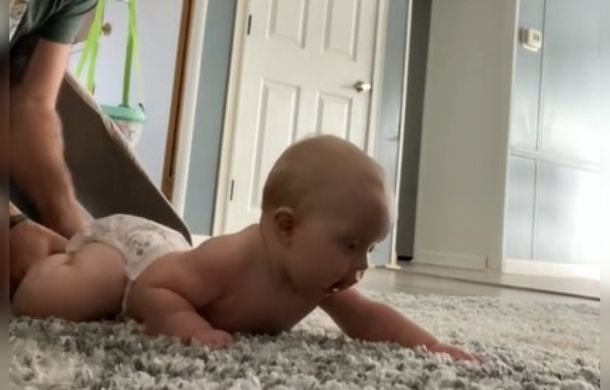 Tummy time is crucial to childe development. Image shows a father and his daughter practicing tummy time.