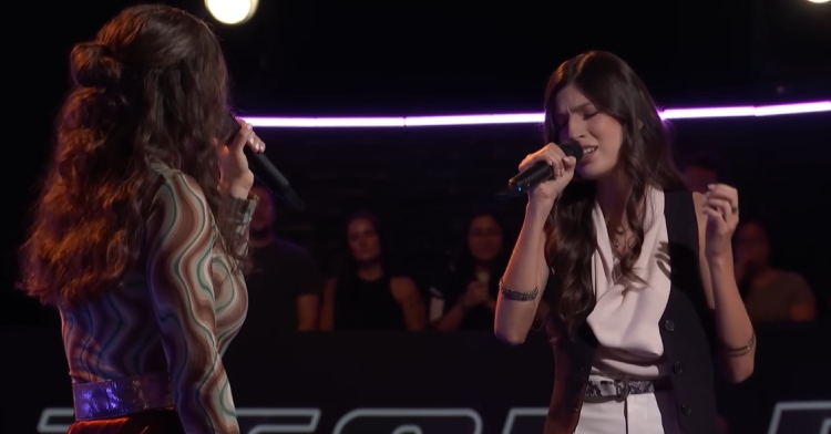 Alison Albrecht and Angelina Nazarian sing together on "The Voice." From this view we can see Alison's back and Angelina's face as she sings with her eyes closed.