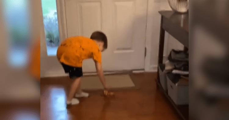 boy placing banana peel on the floor in front of a door