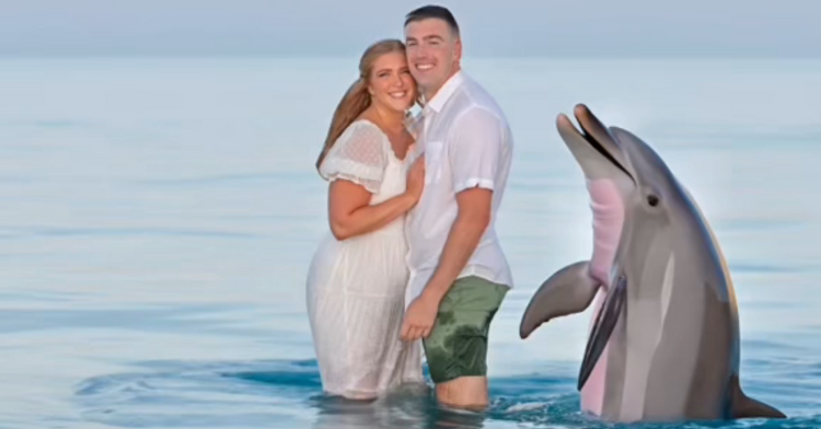 Couple standing next to photoshoped dolphin in the ocean