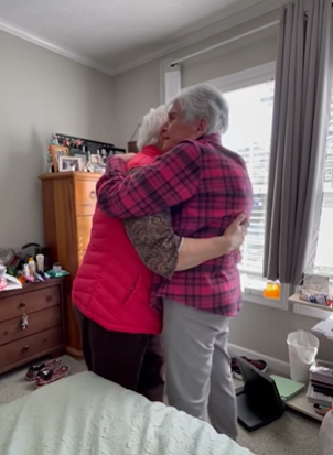 Two best friends in their eighties hug during a surprise visit.