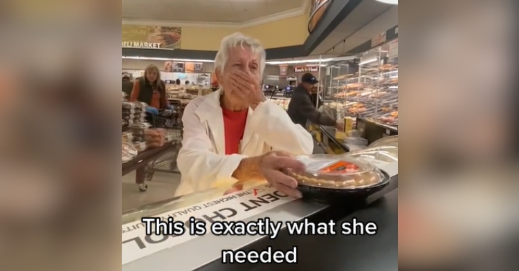 Grandma, who looks emotional, covers her mouth from shock. She's standing at a counter at a deli in a store. Text on the screen reads: "This is exactly what she needed."