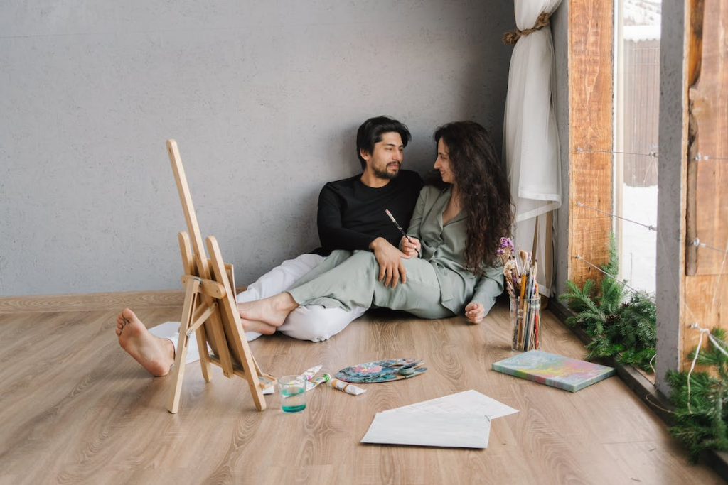 Two people sitting on the floor next to a painting