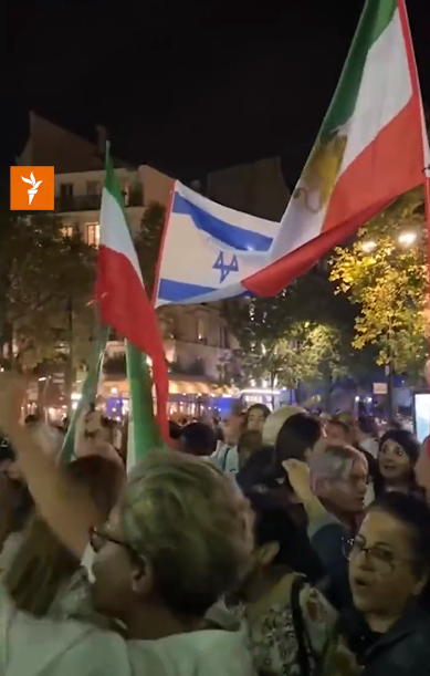 A large group of people in Paris gather in support of victims in the Israeli-Palestinian conflict. Flags are being waved in the air.
