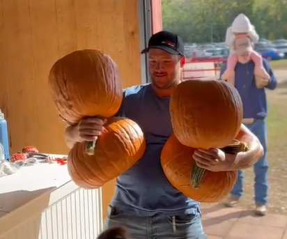 man carrying four pumpkins