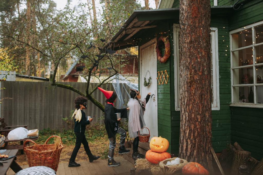 View of three kids walking up to a door to for trick-or-treating.
