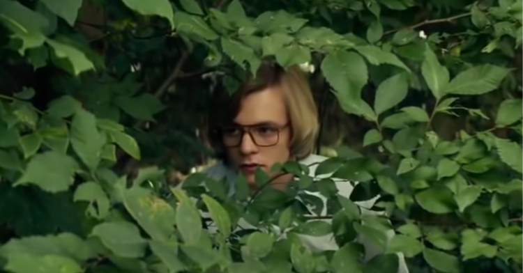 man hiding peering in bushes