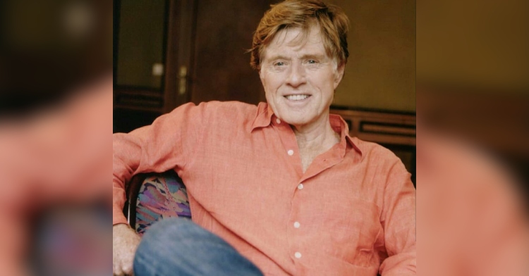 Robert Redford smiles as he sits and poses for a photo.