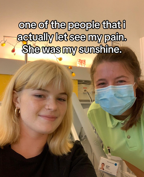 Romy smiles softy from a hospital bed as she takes a selfie with someone wearing a face mask. This person also has a tag on their shirt with their photo, indicating it may be a medical professional. Text on the image reads: "One of the people that I actually let see my pain. She was my sunshine."