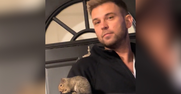 Close up of a man standing at a door as a squirrel rests on his arm.