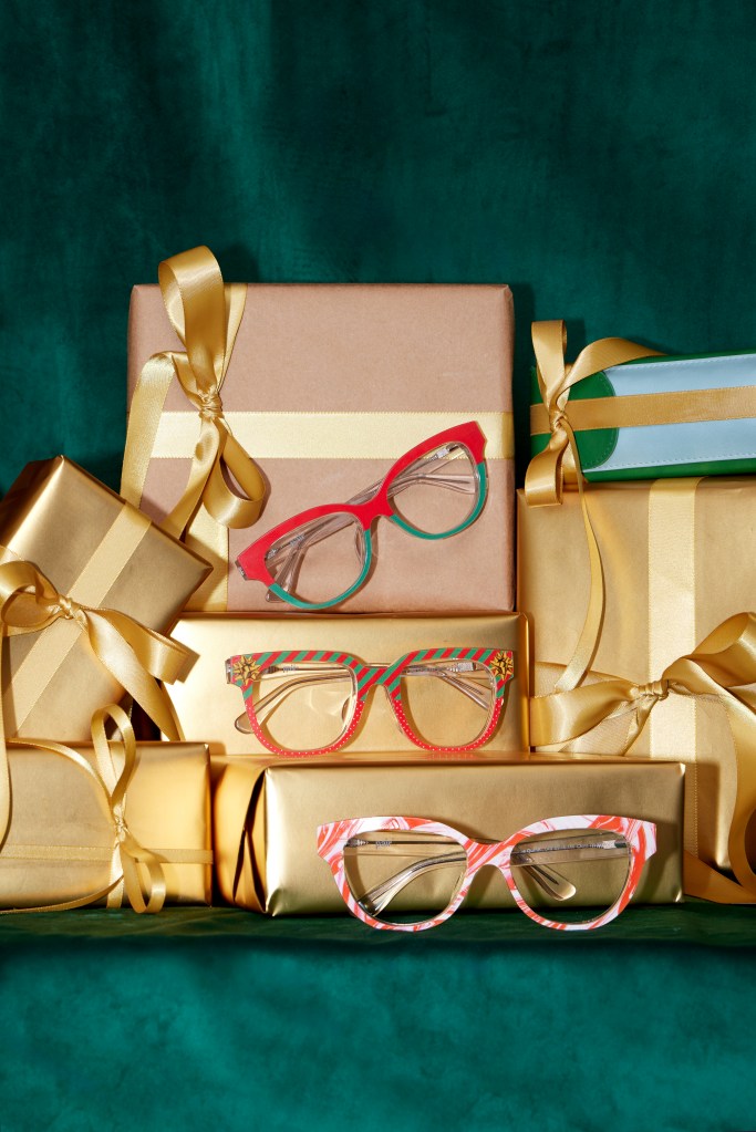 Festive gifts wrapped in gold colored paper are stacked on each other. Three pairs of glasses from Pair's Holiday selection rest on three separate boxes.
