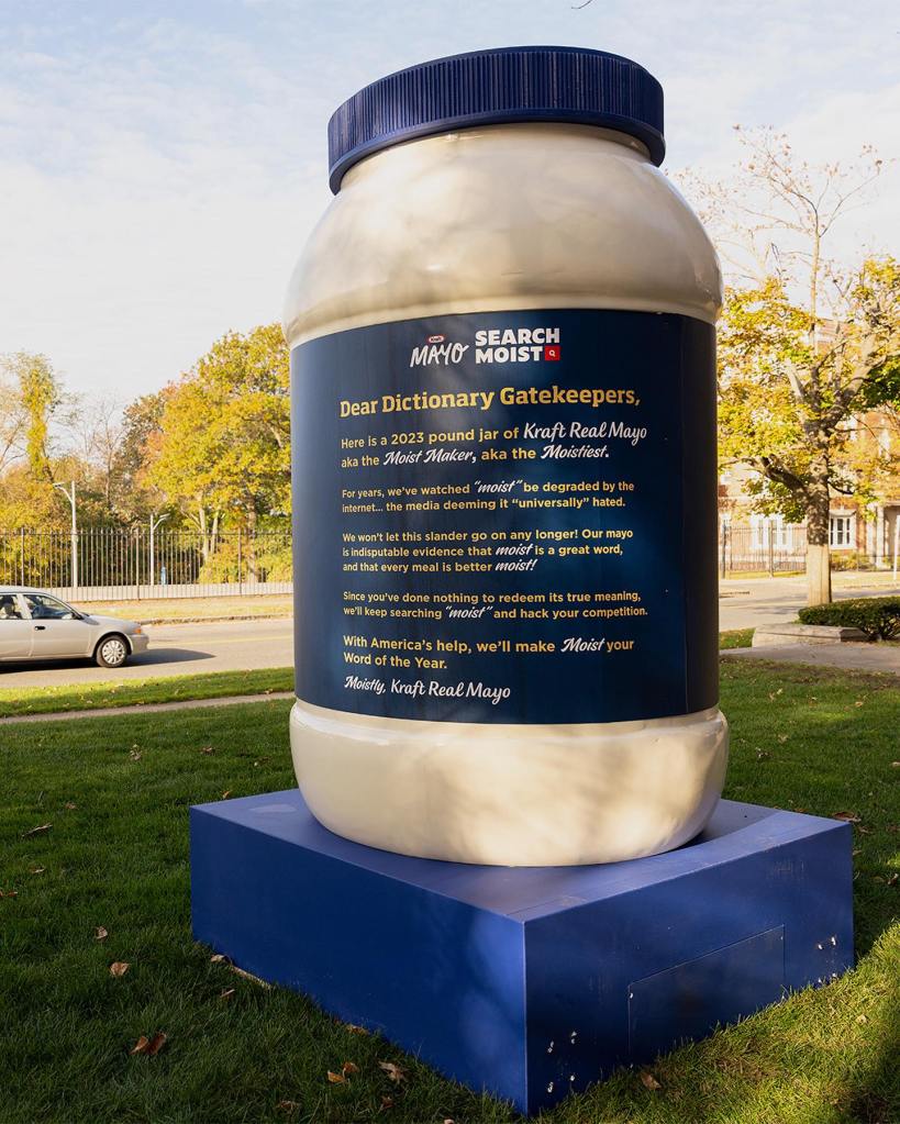 View of the back of the 8 ft. jar of Kraft Mayo they delivered to Merriam-Webster's headquarters. 

The back of the jar reads:

Here is a 2023 pound jar of Kraft Real Mayo aka the Moist Maker, aka the Moistest. 

For years, we've watched "moist" be degraded by the internet... the media deeming it "universally" hated. 

We won't let this slander go on any longer! Our mayo is indisputable evidence that moist is a great word, and that every meal is better moist!

Since you've done nothing to redeem its true meaning, we'll keep searching "moist" and hack your competition.

With America's help, we'll make Moist your Word of the Year.

Moistly, Kraft Real Mayo

