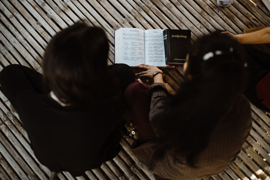 top down view of two girls reading from a book