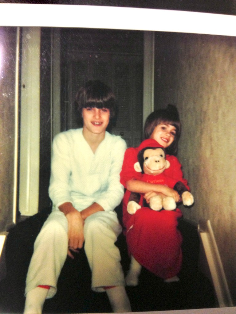 Shawn Killinger, when she was a kid, sits at the top of a staircase with someone who appears to be around her age. She's holding a stuffed moneky.