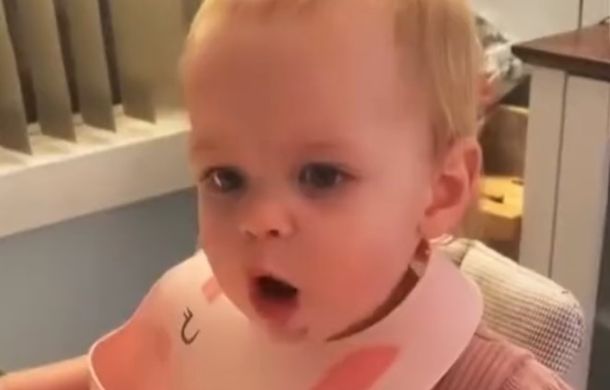 Toddler has a surprised expression after eating pizza for the first time.