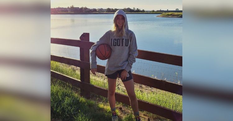 A teenage girl poses with a basketball.