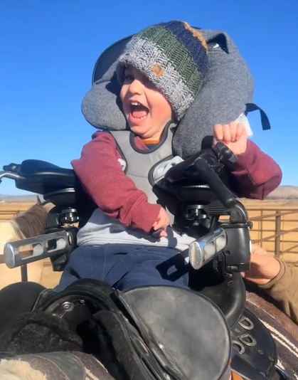 A young boy with cerebral palsy sits in an adaptive saddle. 