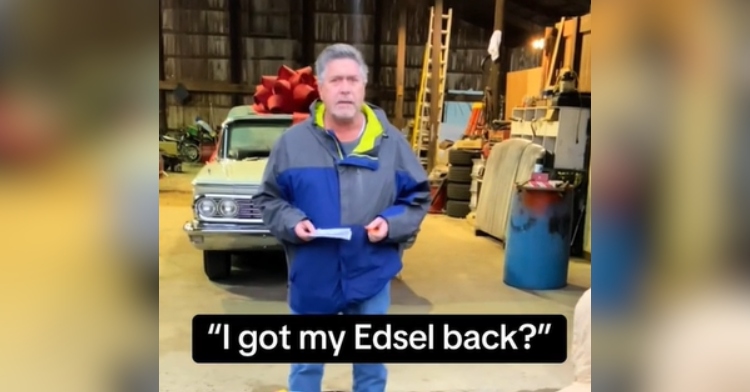 A man stands with his back toward an Edsel car with a giant red bow on top. He has a paper in his hand, and he looks surprised. Text on the image shows what he is saying: "I got my Edsel back?"