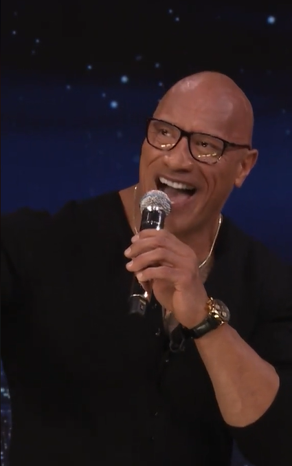 Close up of Dwayne "The Rock" Johnson singing into a mic while on "The Tonight Show Starring Jimmy Fallon."