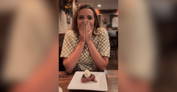 woman sitting at restaurant with hands over face smiling