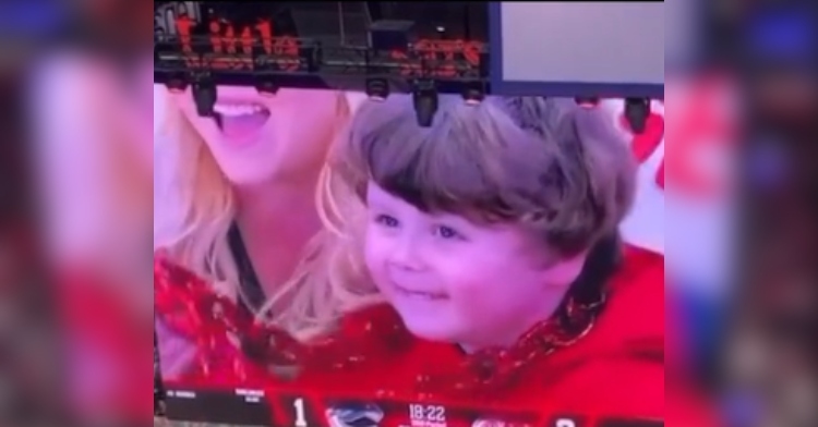 A 4-year-old named George grins as he's shown on the jumbotron at a Detroit Red Wings hockey game.