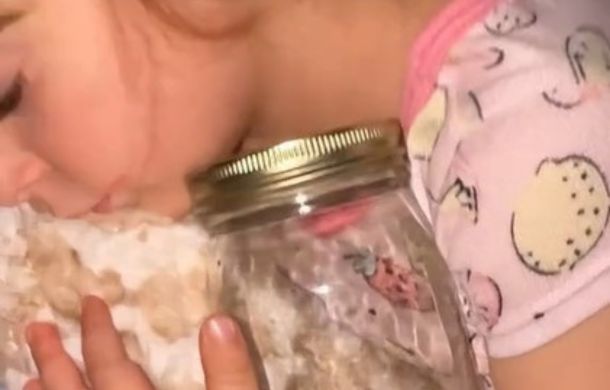 Image shows a sleeping girl, cuddling a jar.