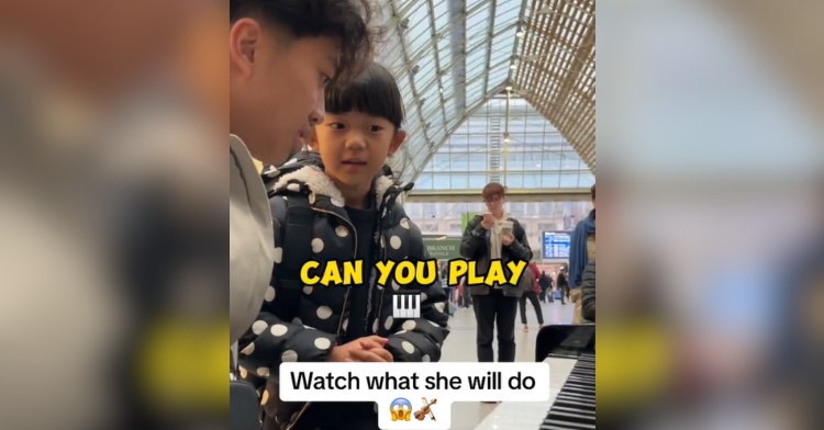 A little girl stands near a pianist sitting at a piano in a train station. What she's saying is in text on the image: "Can you play..." Other text on the image reads: "Watch what she will do" which includes a violin emoji.