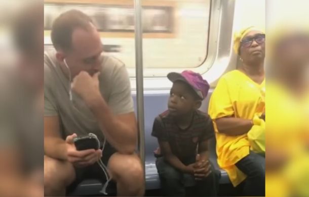 In a heartwarming moment on the subway, a young boy and a man make eye contact.