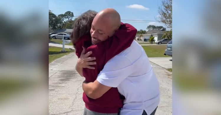 A smiling husband hugs his wife in the street.