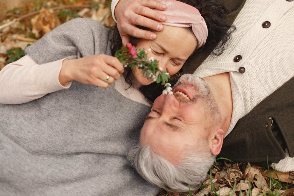 older couple lays together with a flower
