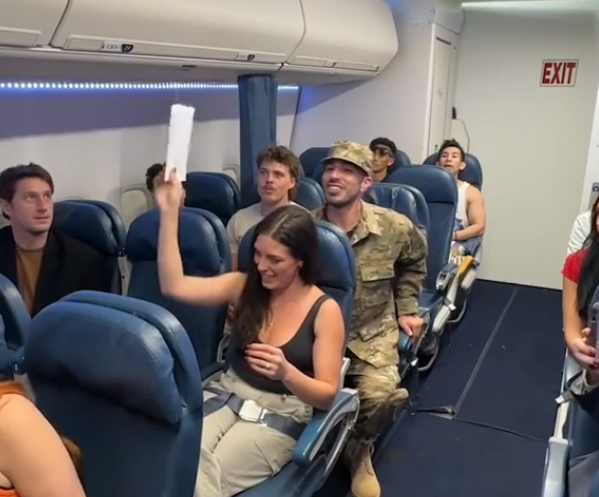 woman recieves envelope for military homecoming surprise on a plane