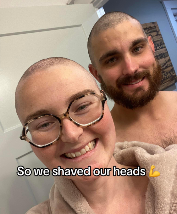 Chelsea, now with a shaved head, smiles as she takes a selfie with her husband who also shaved his head.
Text on the image reads: "So we shaved our heads."