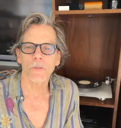 Kevin Bacon, the actor, sits in his home in front of a record player.
