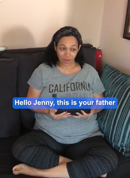 Jennifer Jones-Prothro smiles as her eyes grow wide. She's sitting on a couch, speaker in hand, as she listens to her late father's edited voice used to make a heartwarming gender reveal message. Text on the image shows what is being said: "Hello, Jenny, this is your father"