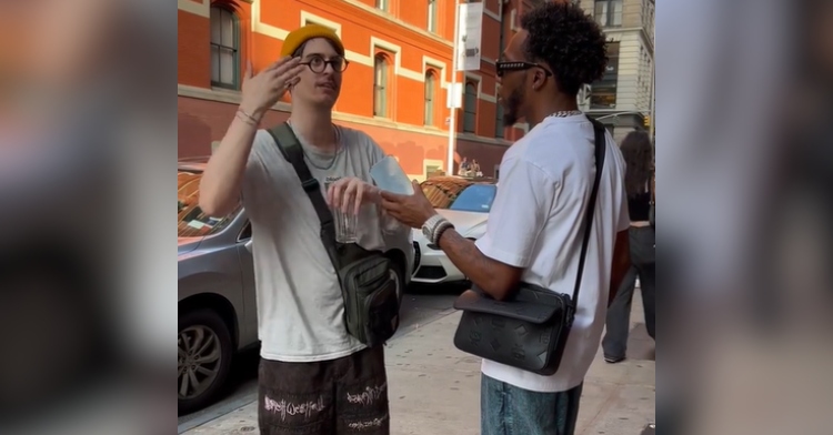 A man wearing a beanie and broken glasses looks up and gestures with one hand as he talks to another man, TikTok user GloJays.