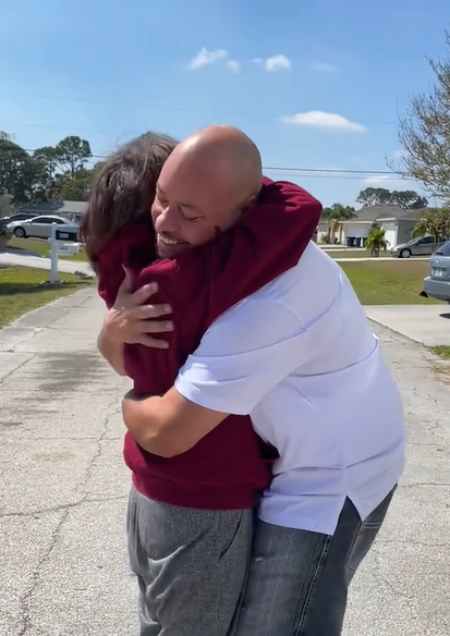 A smiling husband hugs his wife in the street.