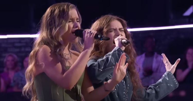 Claudia and Mara sing passionately on "The Voice." They're basically mirroring each other - both have their eyes closed and are holding the mic in their right hands and are holding out their left hands in a similar position.