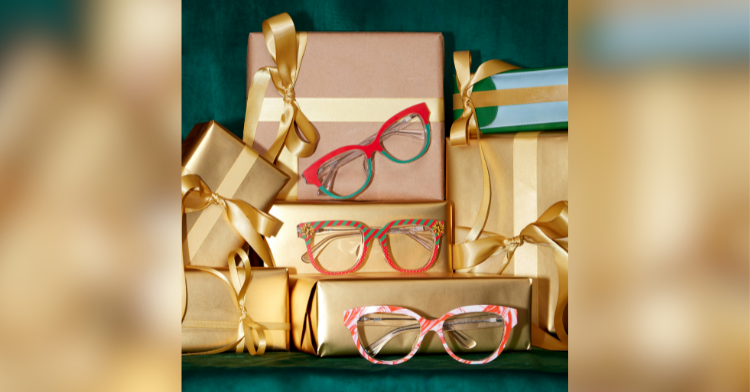 Festive gifts wrapped in gold colored paper are stacked on each other. Three pairs of glasses from Pair's Holiday selection rest on three separate boxes.