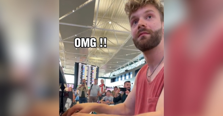 Side view of a man playing a piano at an airport. The man is looking up at something we can't see in the image. His eyes are wide with surprise. Text in the image reads: OMG