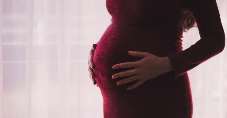 A pregnant woman wearing a red dress at work.