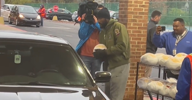 Shaq Leonard carries a turkey over to a car that's parked next to him. Someone with a camera captures the moment.
