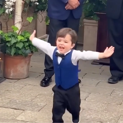 A little toddler runs down the aisle at his mom's wedding with open arms. 