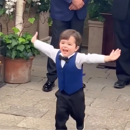 A little toddler runs down the aisle at his mom's wedding with open arms.