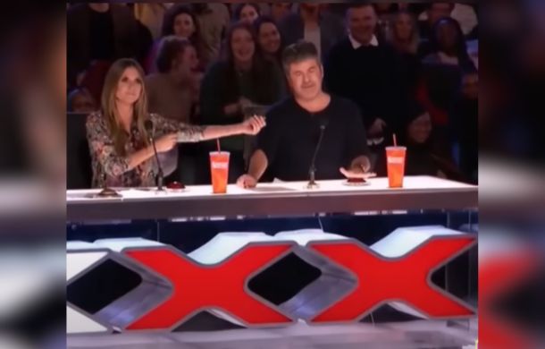 Image shows Heidi Klum and Simon Cowell just as Simon presses the red buzzer.